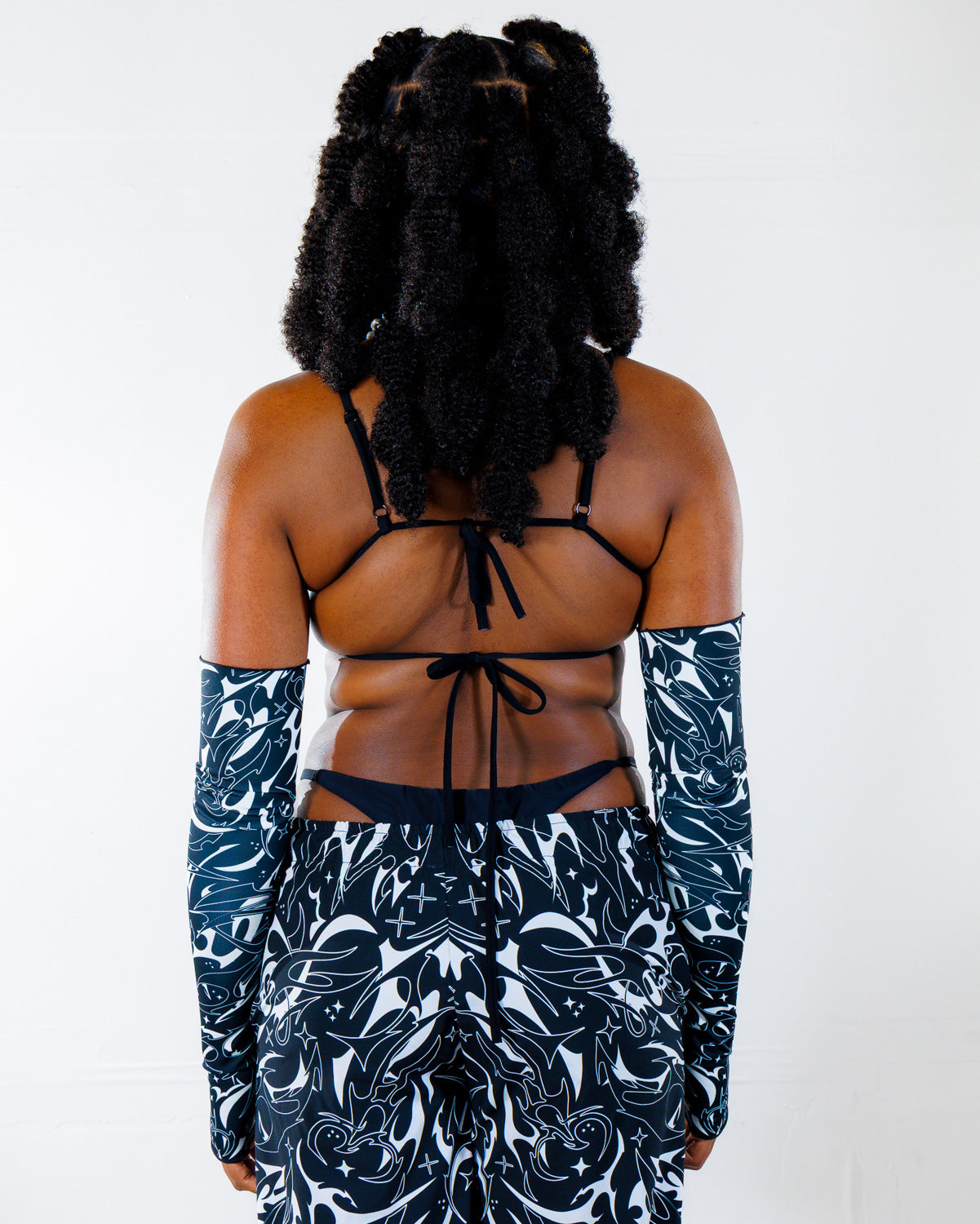 BLVDE Wonder Top shown from the back, featuring a black tie-back bikini top and matching patterned sleeves, perfect for a rave festival.