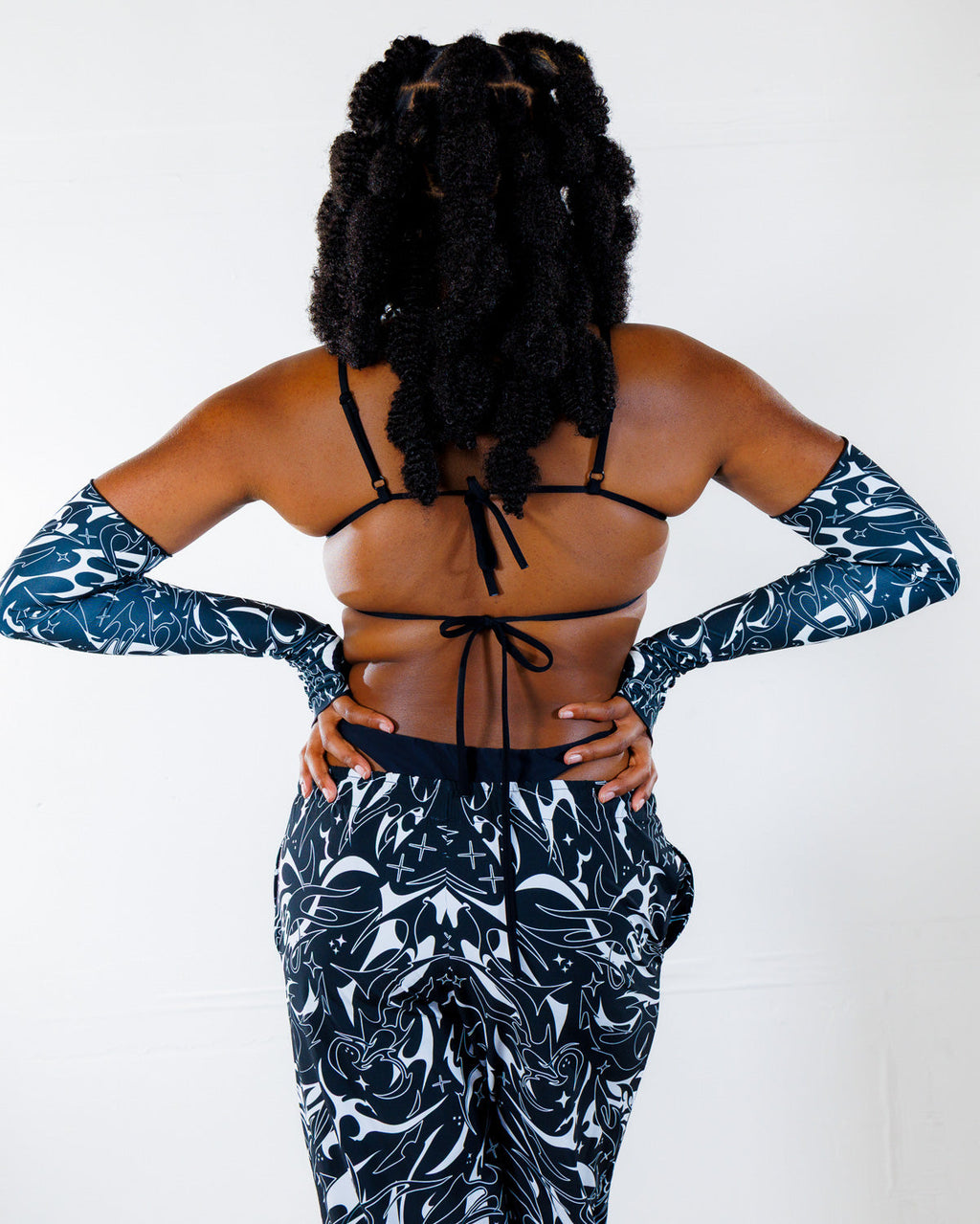BLVDE Wonder Top shown from the back, featuring a black bikini-style top with ties and matching black and white patterned long sleeves and pants, ideal for festival wear.