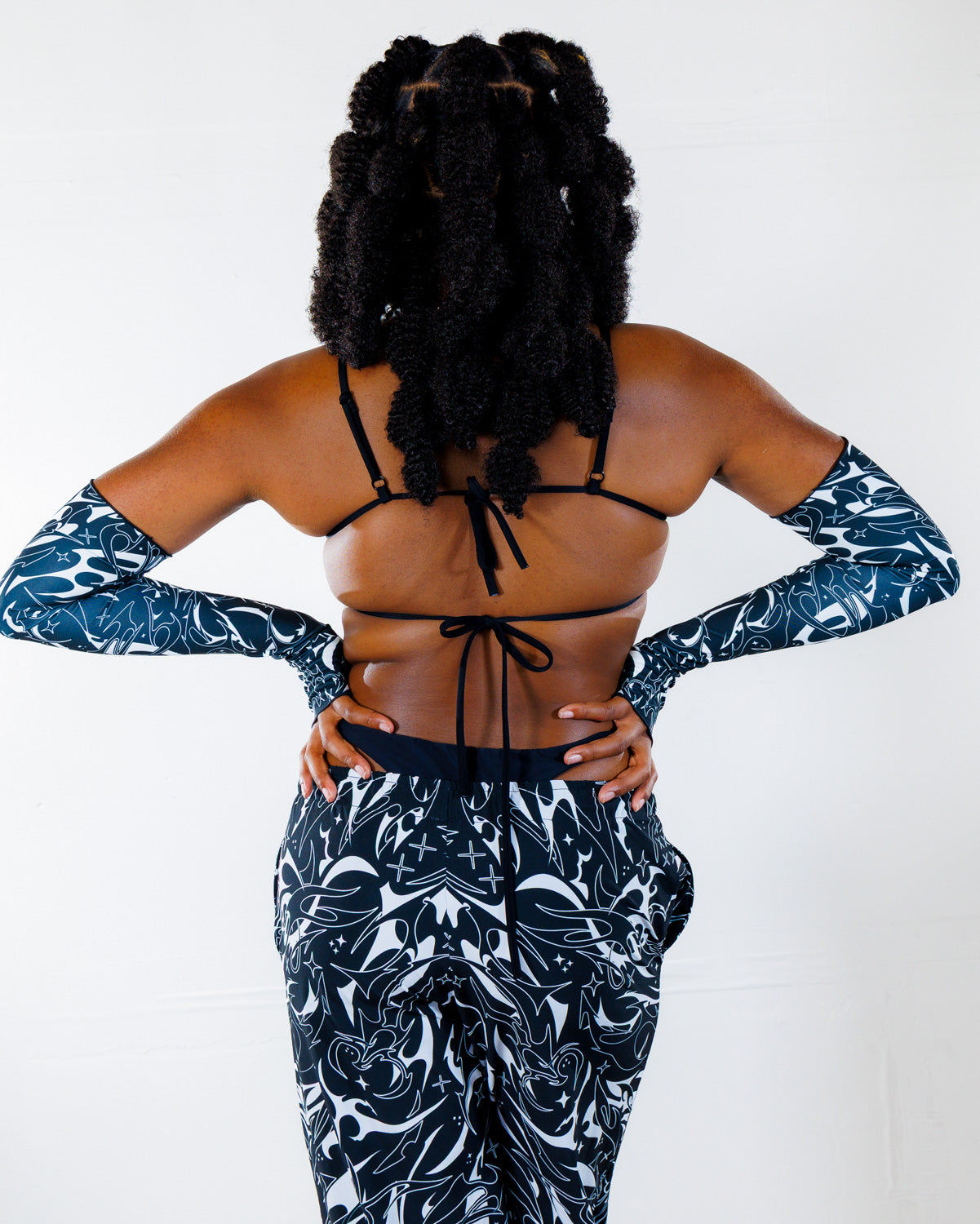 BLVDE Wonder Top shown from the back, featuring a black bikini-style top with ties and matching black and white patterned long sleeves and pants, ideal for festival wear.