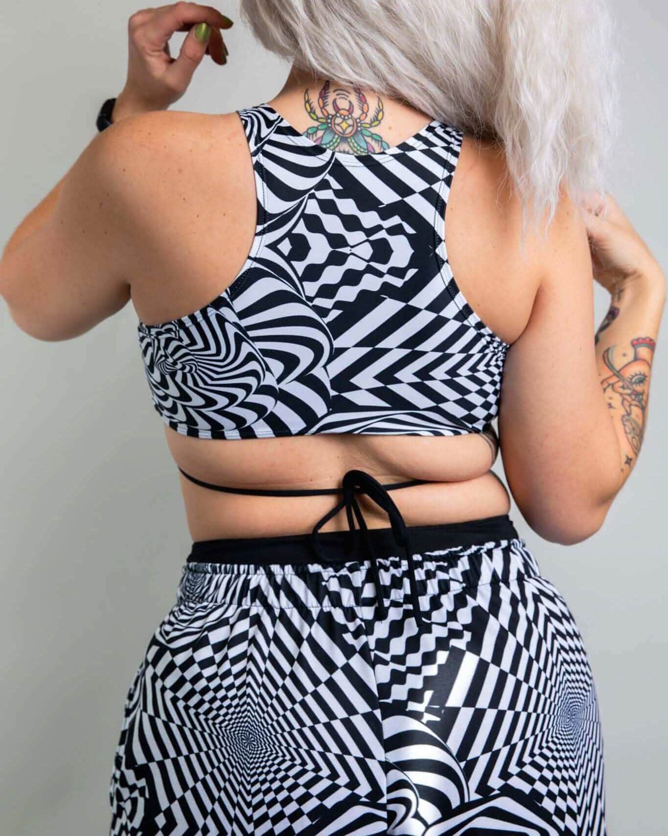 Back view of distortion geometric rave top with crisscross straps and matching festival bottoms