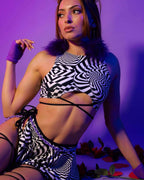 Distortion rave top with geometric black white pattern and strappy underboob design modeled against purple background