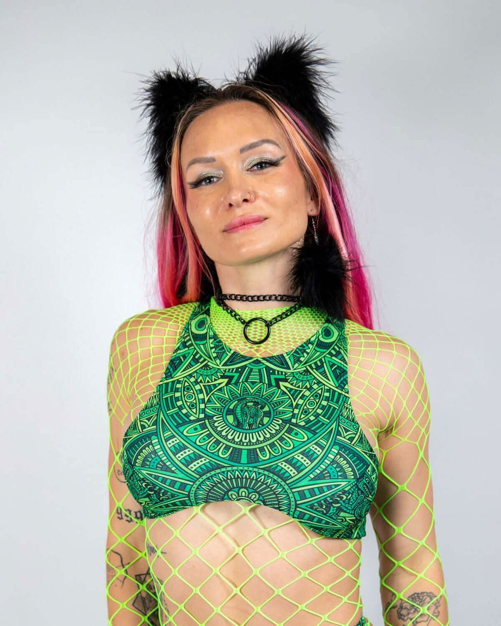 Dominion Teaser Top in green with intricate patterns, worn by a woman in a neon green fishnet top, front view, perfect for rave festivals.