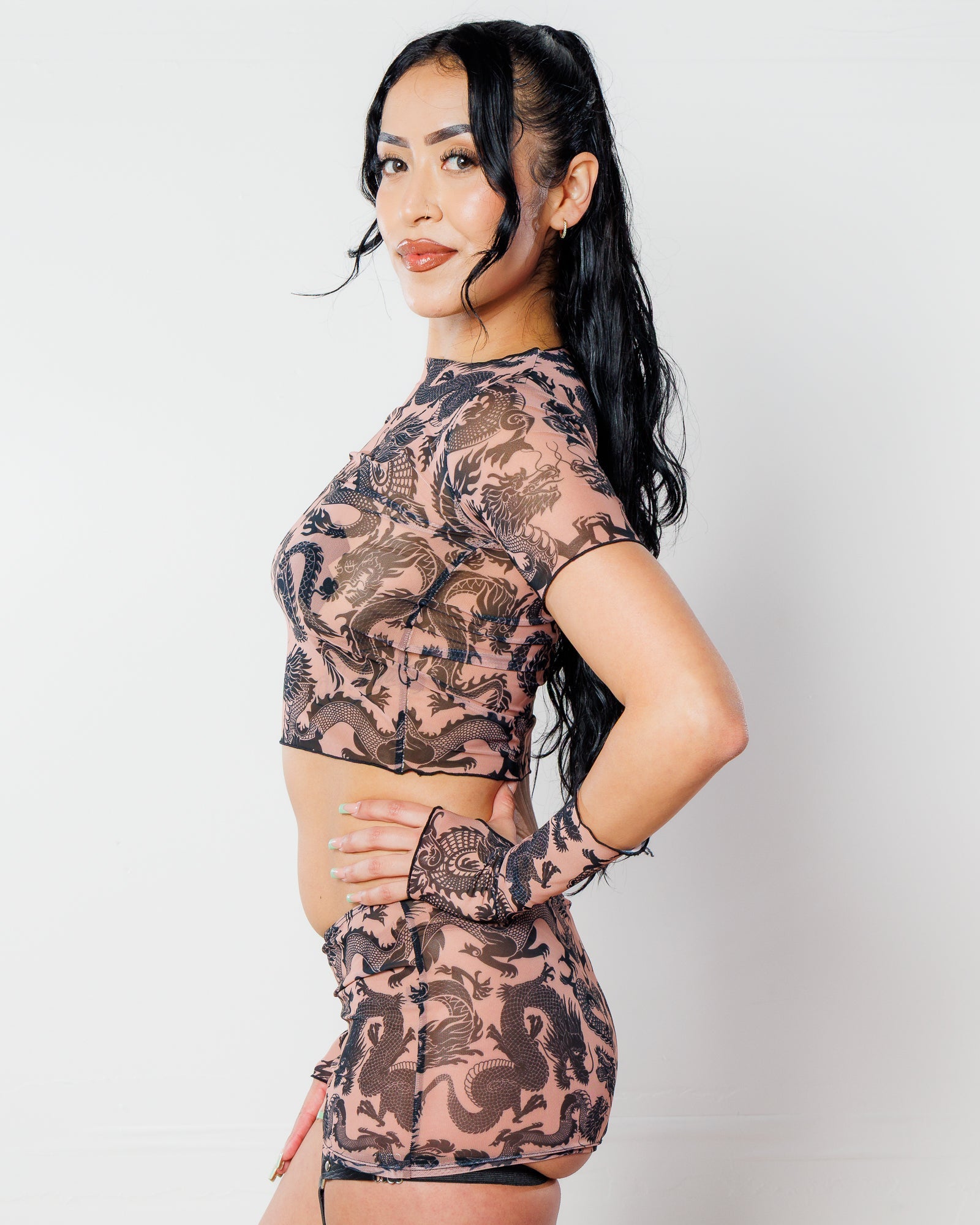 Dynasty Baby Tee in nude mesh with black dragon print, seen from the side on a model, perfect for rave festivals.