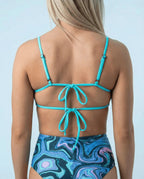 Glacial Wonder Top back view, featuring turquoise straps tied in bows, paired with high-waisted rave bottoms.
