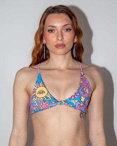 Groovy Serendipity Top front view, showcasing the pastel rave bikini top with peace signs, daisies, and a third-eye sun.