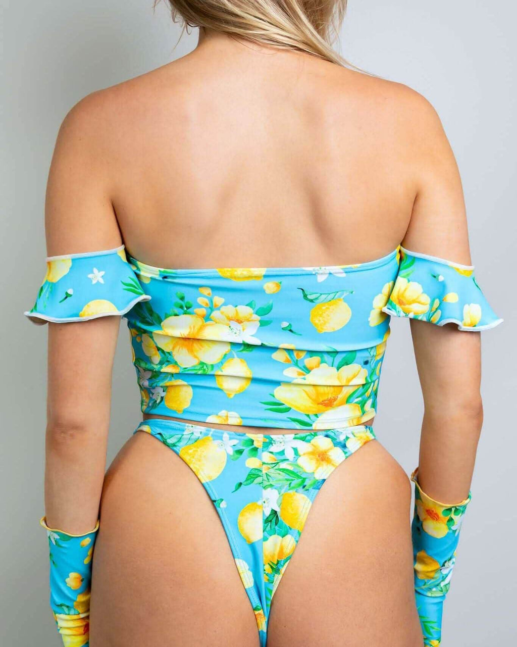 Back view of Lemon Drop rave top with off-shoulder sleeves and matching bottoms in bright blue lemon print