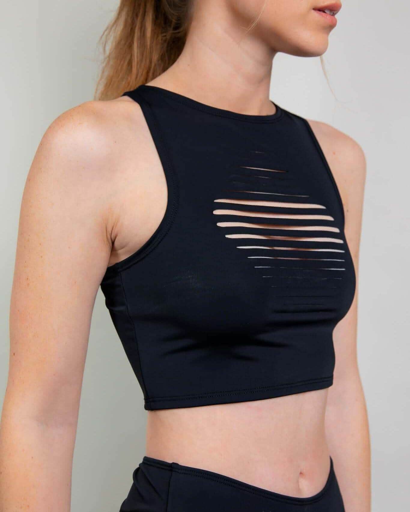 Matte black slit rave top with horizontal cutouts modeled from side angle for festival outfit styling