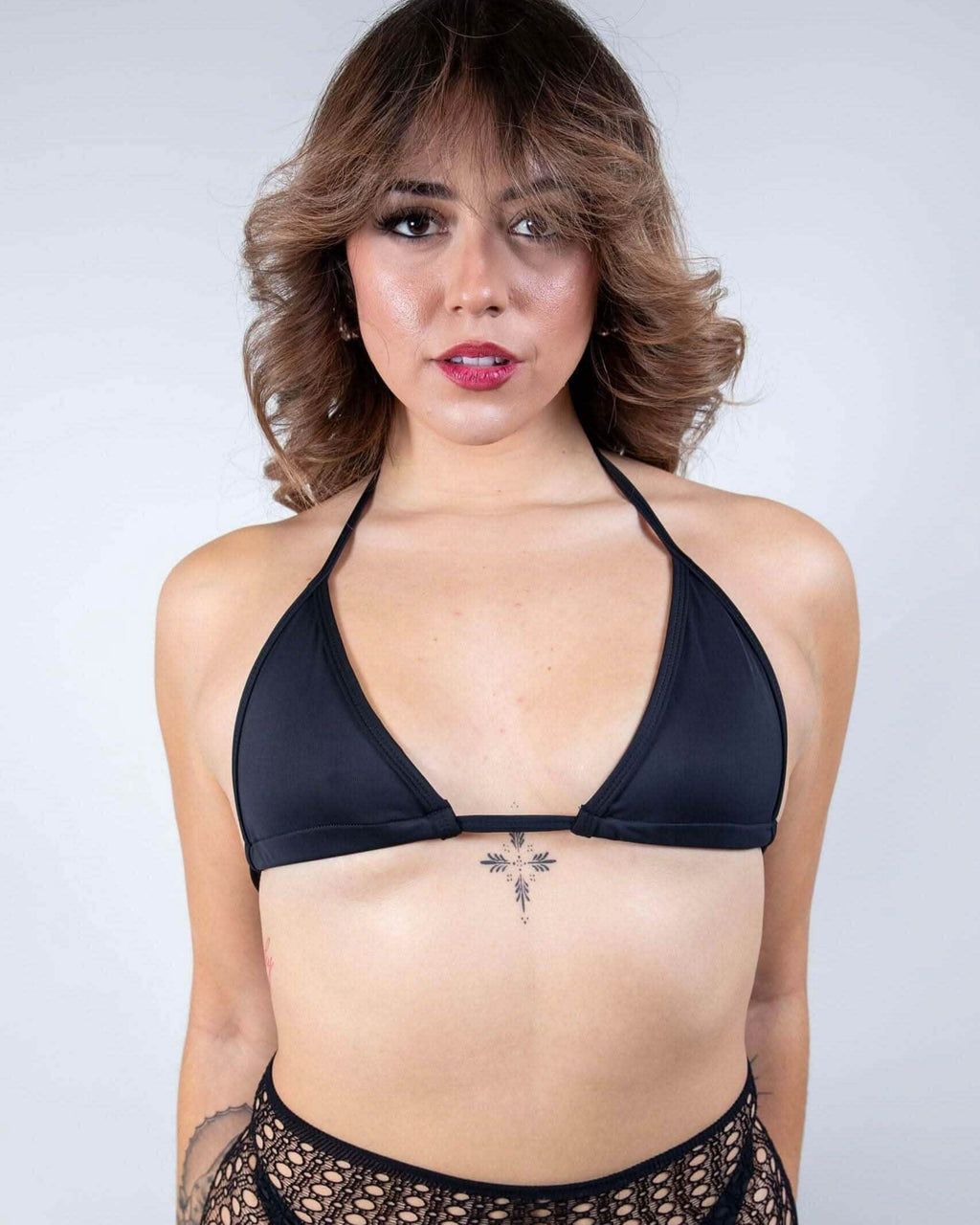 Woman wearing matte black triangle rave top with halter ties, festival bikini front view