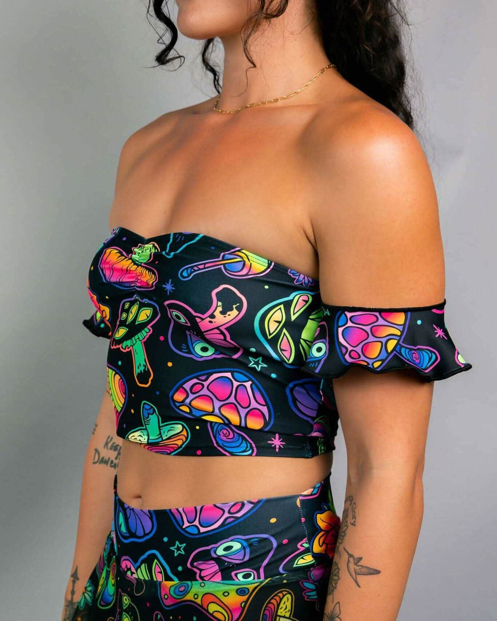 Psychedelic mushroom print rave top with off-shoulder ruffle sleeves, side view of festival outfit on model