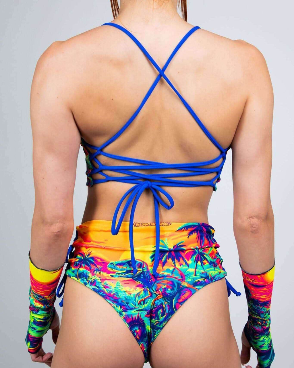 Back view of Saurian reversible rave top with blue cross-back straps and tropical print festival outfit