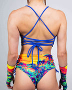 Back view of Saurian reversible rave top with blue cross-back straps and tropical print festival outfit