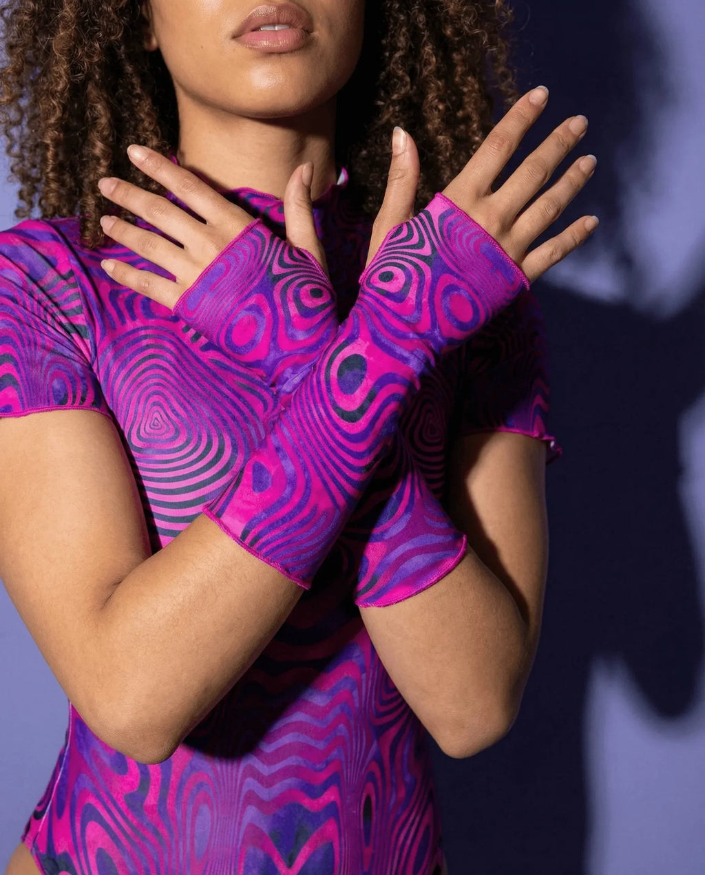 Model showcasing Vanish rave arm sleeves with pink purple swirls in defensive hand pose