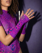 Model showcasing pink purple Vanish pattern rave arm sleeves in dynamic pose with raised hand