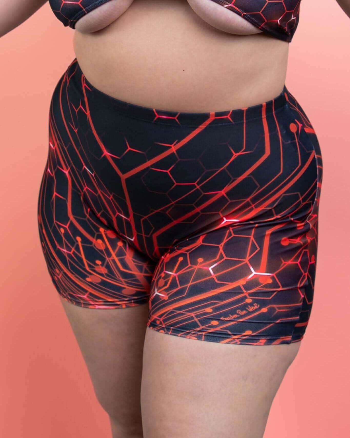 Red Singularity high waist rave pants with geometric pattern, festival outfit front view on coral background
