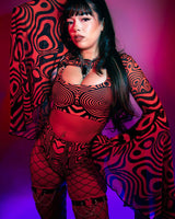 Model in psychedelic red and black outfit with bell sleeves, perfect for rave outfits, posed under colorful lighting.