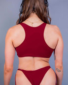 Back view of a model in a scarlet cutout teaser top, showcasing the racerback design and underboob look. Ideal for rave outfits.