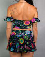 Woman wearing a colorful off-the-shoulder Bardot top and matching skirt, showcasing a playful rave outfit design.