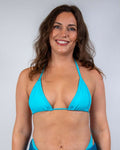 Model wearing the Siren Bikini Top, a vibrant neon-blue triangle bikini, perfect for rave outfits and beach fun.