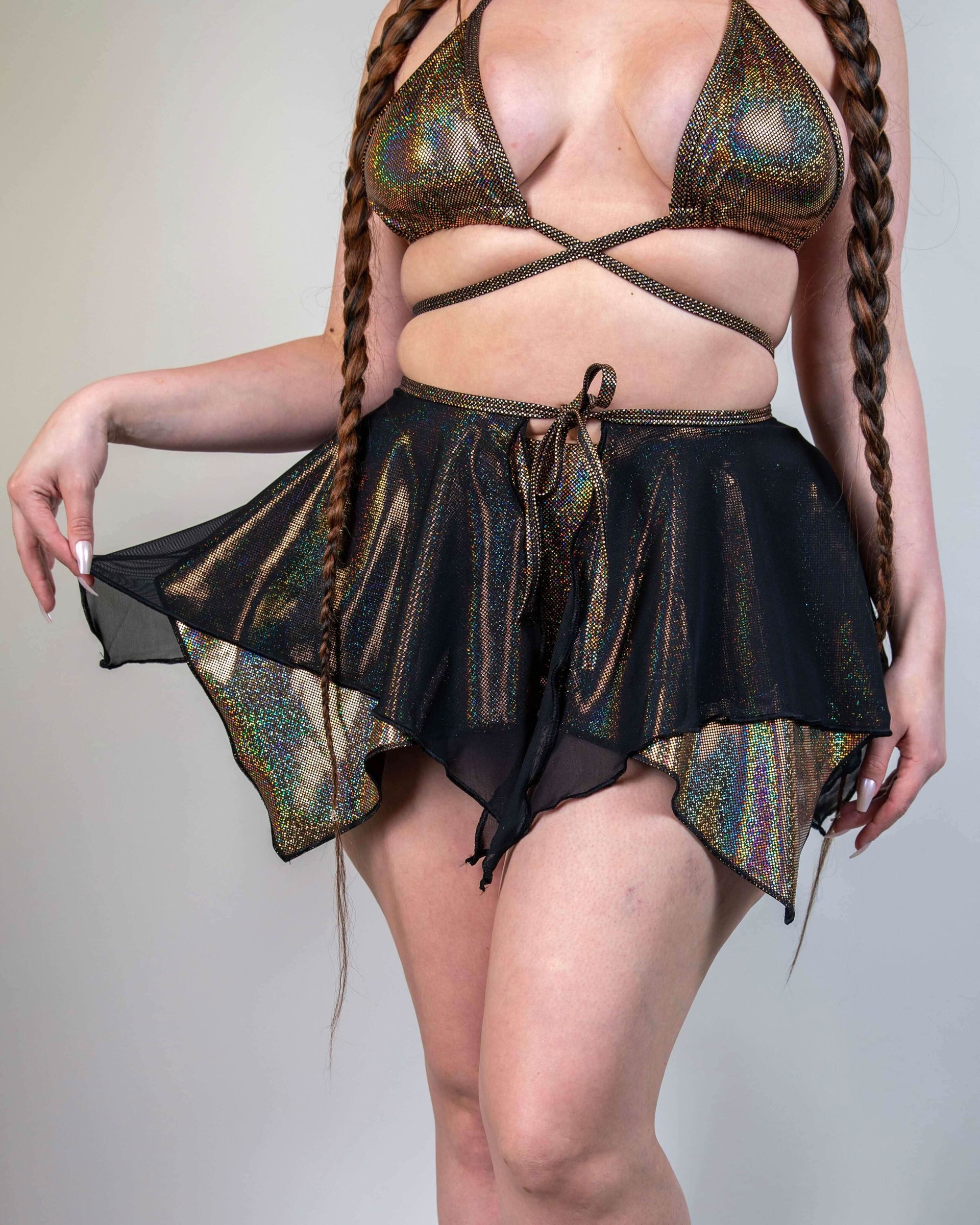 Starfire rave skirt with golden holographic shimmer and black mesh overlay modeled from front for festival outfit styling