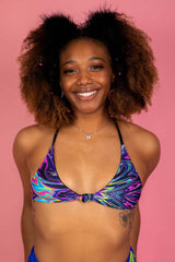 Radiant model showcasing AstroFlare Serendipity Rave Top with a psychedelic swirl pattern, accentuating a joyful vibe against a pink backdrop