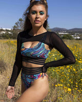 Model wearing black mesh Baelien sleeves with a colorful rave outfit in a vibrant outdoor setting.