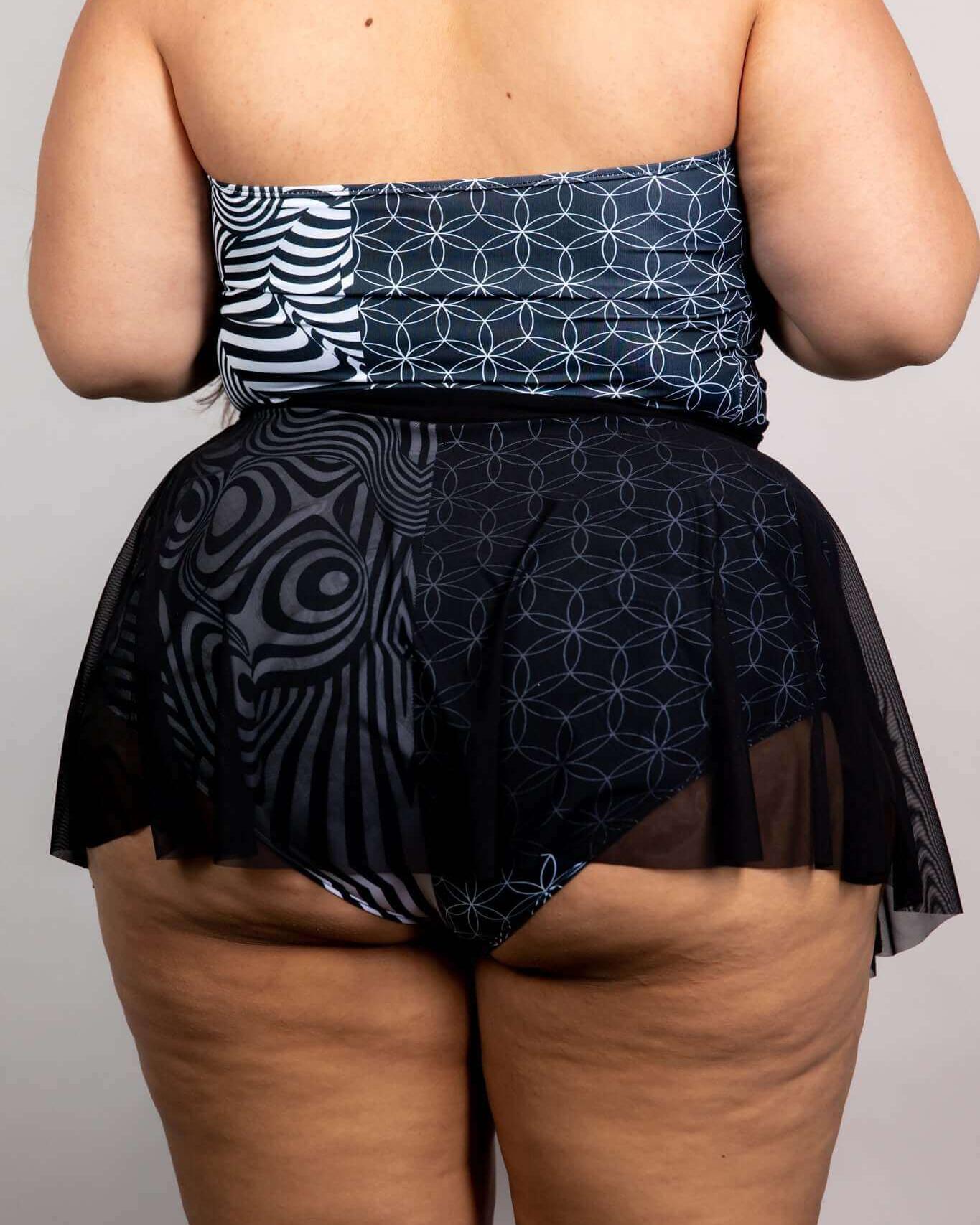 Woman in a stylish black mesh skater skirt with a patterned top, showcasing a chic look from the back.