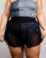 Black mesh skater skirt paired with geometric patterned top, perfect for rave outfits and stylish casual wear.