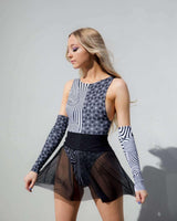 Model wearing a stylish black mesh skater skirt and abstract patterned top, perfect for rave outfits and festival season.