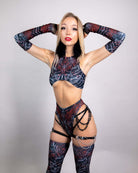 Model showcasing a stylish rave outfit with a black and red pattern, featuring gloves and harness-style accessories.