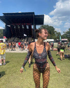Festival-goer wearing the Darkness Temptation Cheeky One Piece swimsuit at an outdoor rave, showcasing an edgy style.