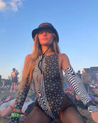 Woman wearing black and white Duality Arm Sleeves and a hat at a festival, showcasing a stylish rave outfit.
