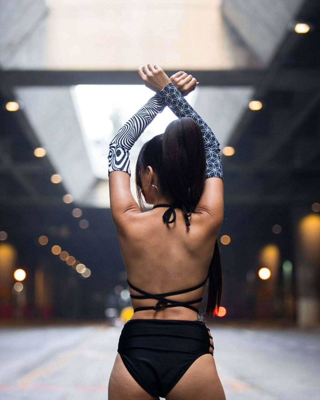 Model showcasing FRW Duality Arm Sleeves with graphic print, styled for rave outfits in an urban setting.