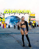 Woman in edgy rave outfit at Countdown festival, showcasing Duality High Waisted Brazilian Bottoms and vibrant stage backdrop.