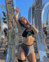 Model wearing Duality High Waisted Brazilian Bottoms in festival attire with trippy black and white pattern, showcasing rave style.