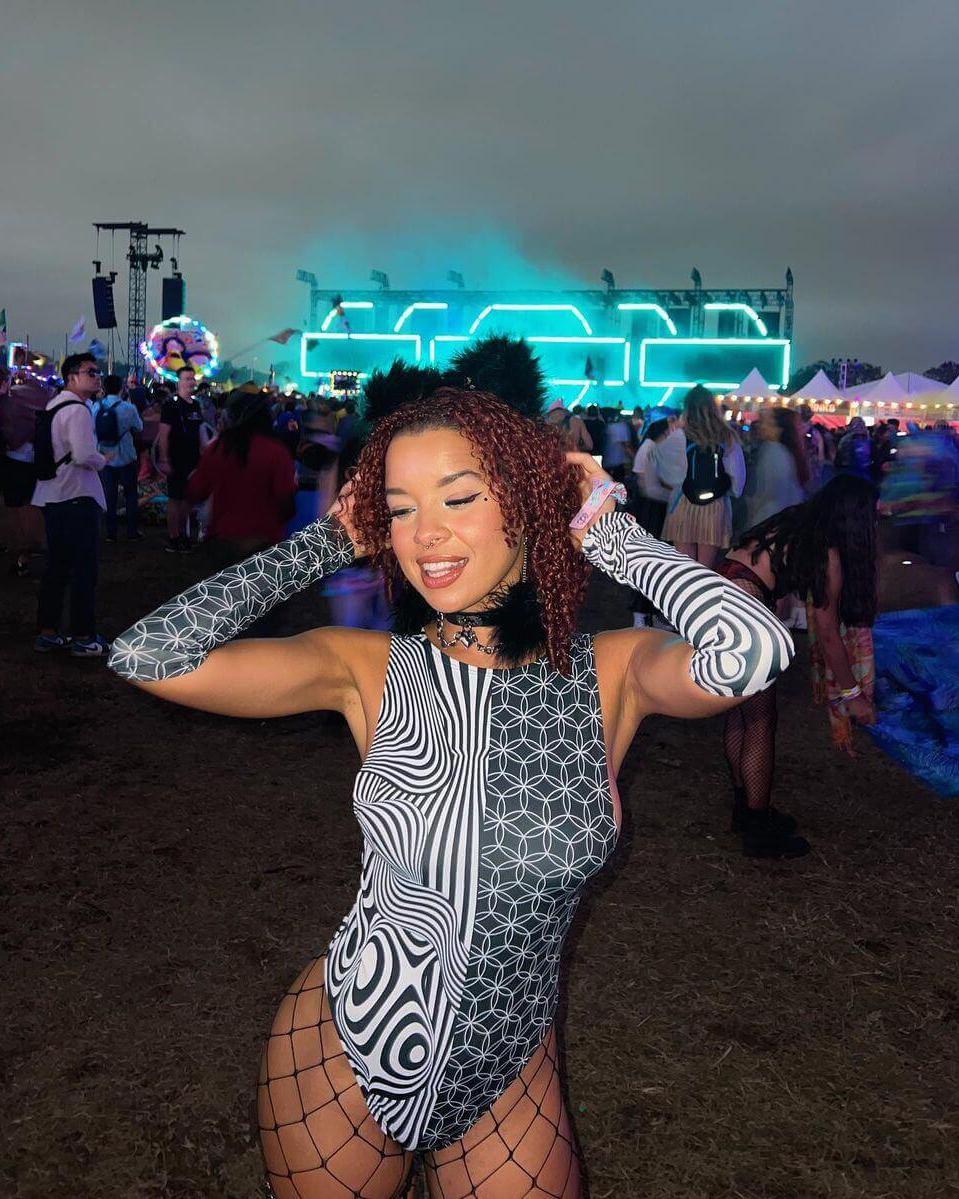 Duality Sideboob Bodysuit showcased at an EDM festival, featuring black and white split design and stylish rave accessories.