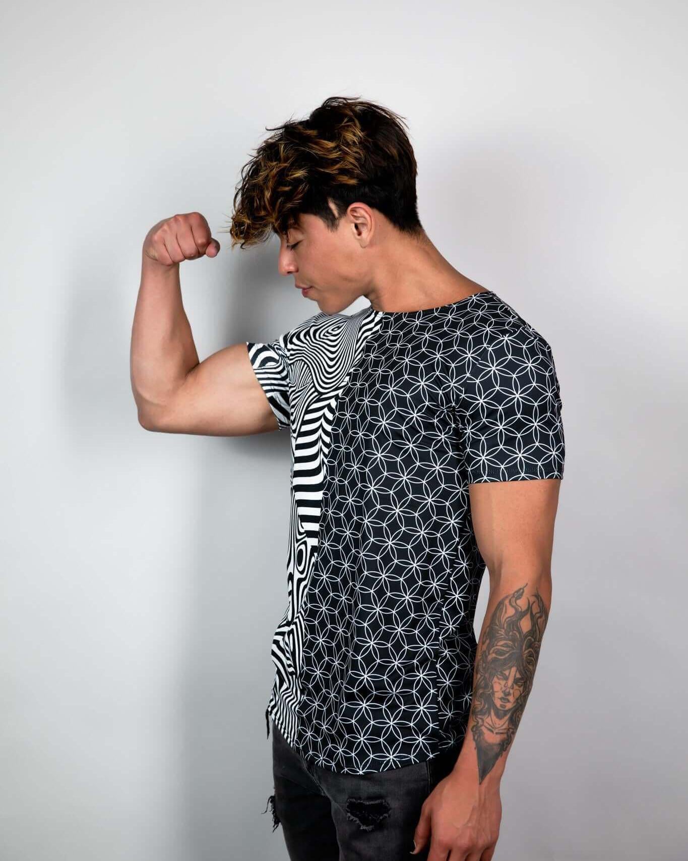 Young man flexing in a Duality Unisex T-Shirt with black-and-white graphic print, showcasing sustainable fashion.