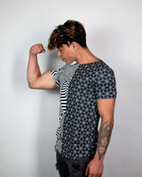 Young man flexing in a Duality Unisex T-Shirt with black-and-white graphic print, showcasing sustainable fashion.