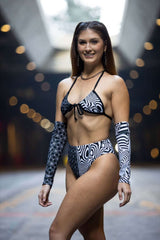 Model showcasing the Duality Wrap Bikini Top in a modern black and white graphic design, perfect for rave outfits.