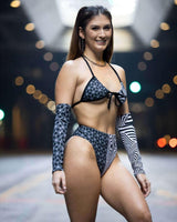Model showcasing the Duality Wrap Bikini Top with black and white graphic design, perfect for summer rave outfits.