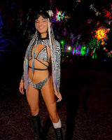 Model in black and white graphic duality wrap bikini top at a vibrant rave event, showcasing stylish festival fashion.
