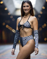 Model showcasing the Duality Wrap Bikini Top in a modern black and white graphic design, perfect for rave outfits.