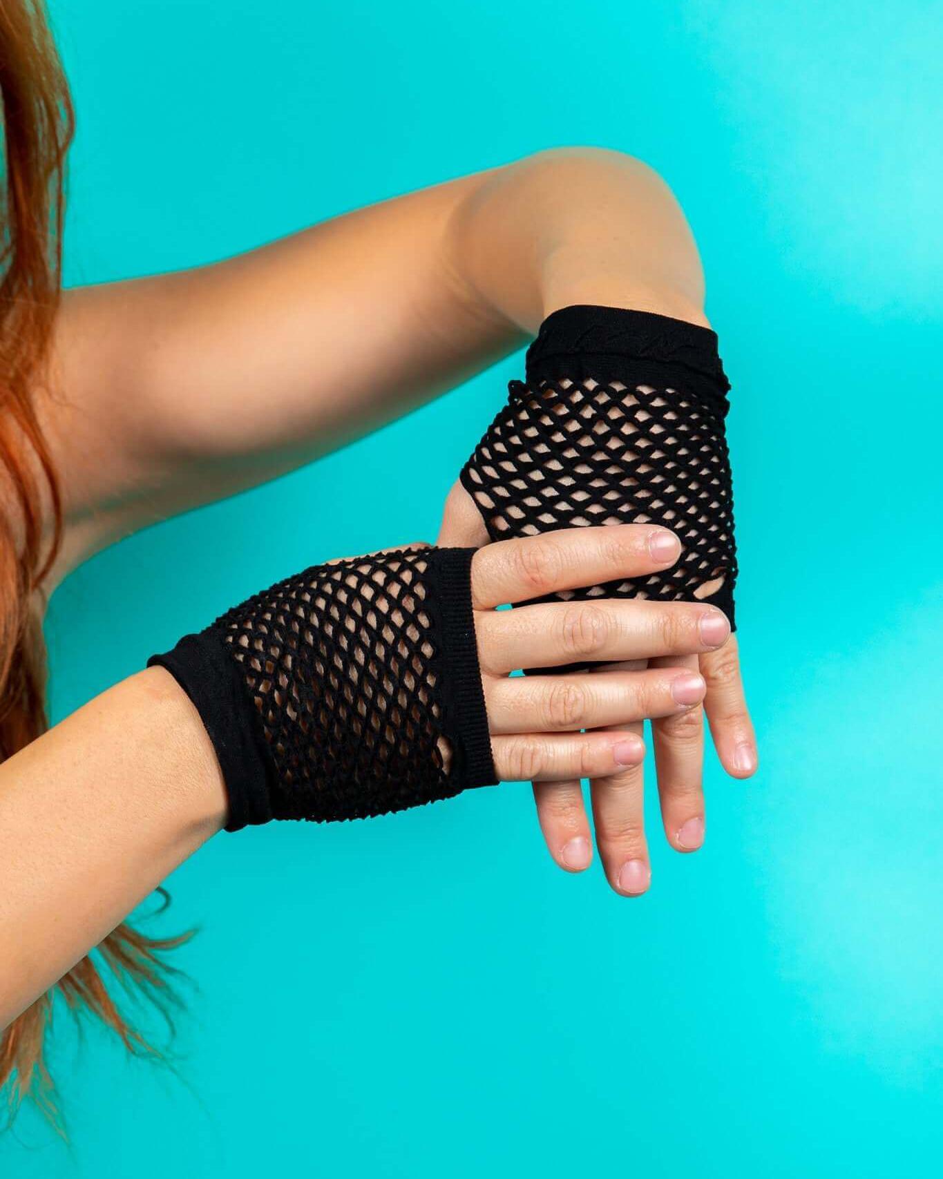 Black fishnet gloves on a woman's hands against a teal background, perfect for rave outfits and festival looks.