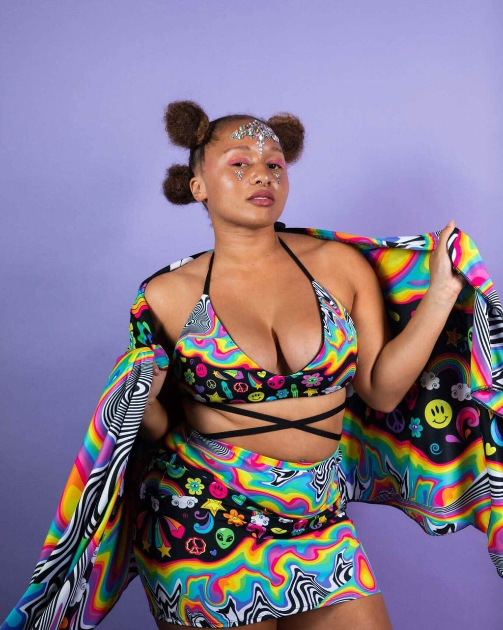 Model wearing HAPPIER Extra Mile Bralette and matching skirt, showcasing a vibrant trippy rainbow print, ideal for rave outfits.