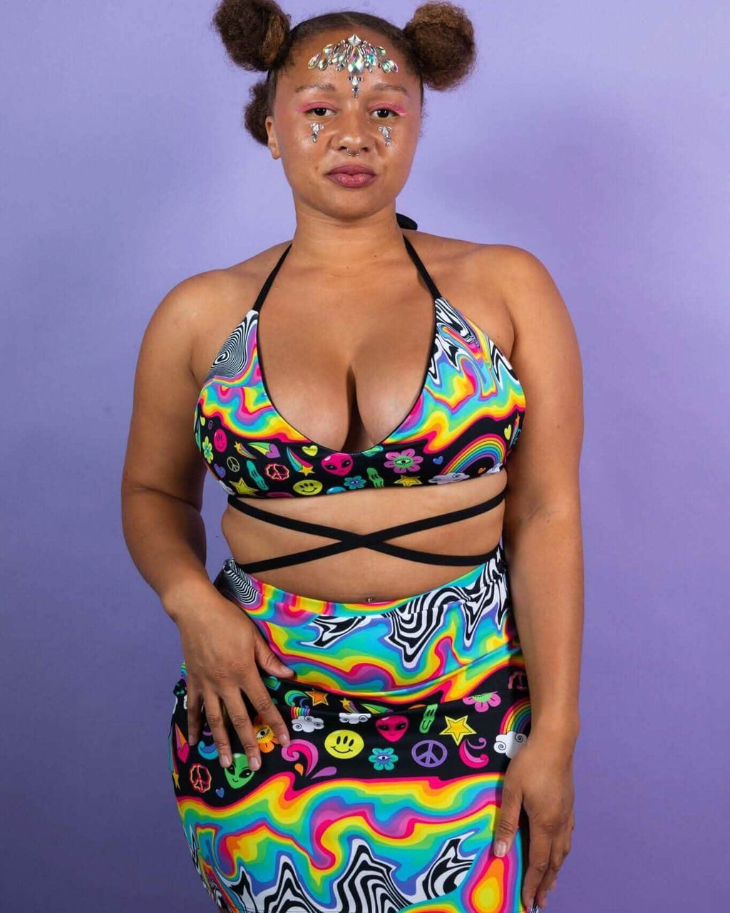 Model wearing the HAPPIER Extra Mile Bralette in vibrant rainbow print, showcasing a trendy rave outfit style.
