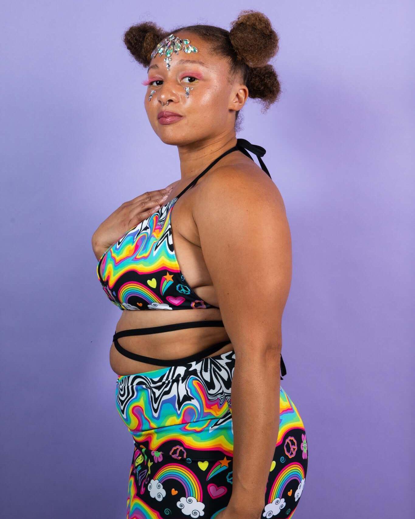 Model showcasing the HAPPIER Extra Mile Bralette in vibrant rainbow print, perfect for rave outfits and festival fashion.