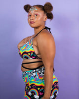 Model showcasing the HAPPIER Extra Mile Bralette in vibrant rainbow print, perfect for rave outfits and festival fashion.