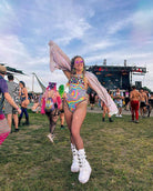 Vibrant woman in psychedelic rainbow bodysuit at EDM festival, showcasing trendy rave outfits and summer festival fun.