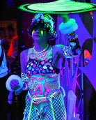 Model in a colorful, psychedelic bodysuit performing at an EDM festival, showcasing vibrant rave fashion.