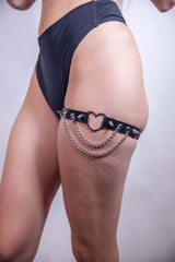 Black heart spike leg garter with chain detailing, perfect for edgy rave outfits and bold fashion statements.