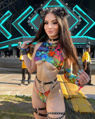 Young woman in colorful rave outfit with body chain at a music festival, showcasing bold festival style and accessories.